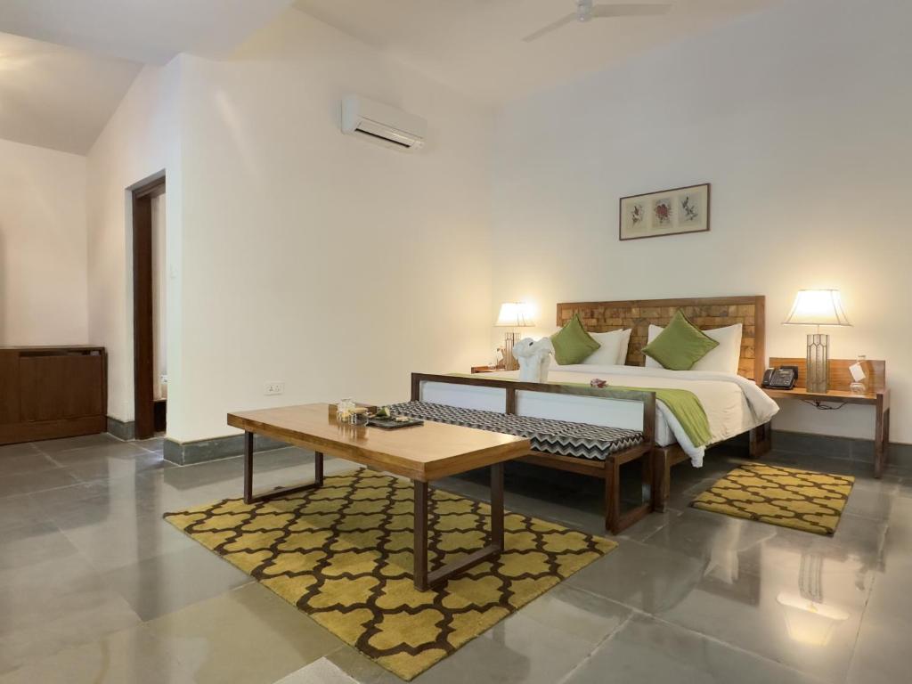 a bedroom with a bed with a table and a bench at Saraca Resort & Spa Corbett in Garjia
