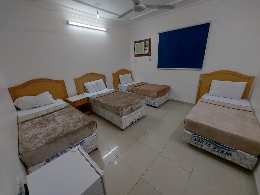 a room with four beds and a blue board on the wall at Jawad Al Dham in Medina