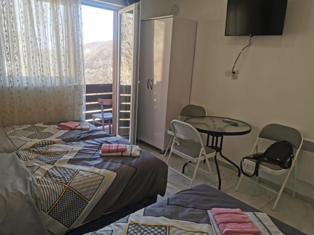una camera con due letti e un tavolo con sedie di Apartman Aleksandar 1 a Ribarska Banja