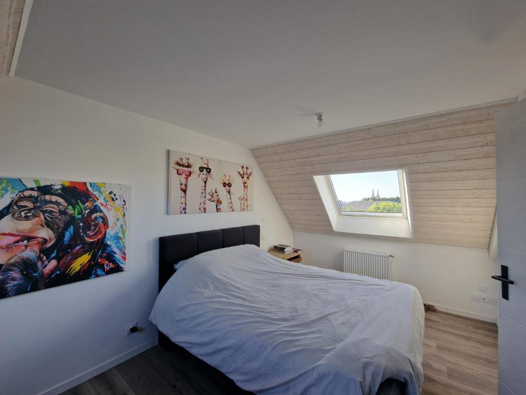 a bedroom with a bed with a painting on the wall at Chambre en centre ville proche mer in Saint-Pol-de-Léon