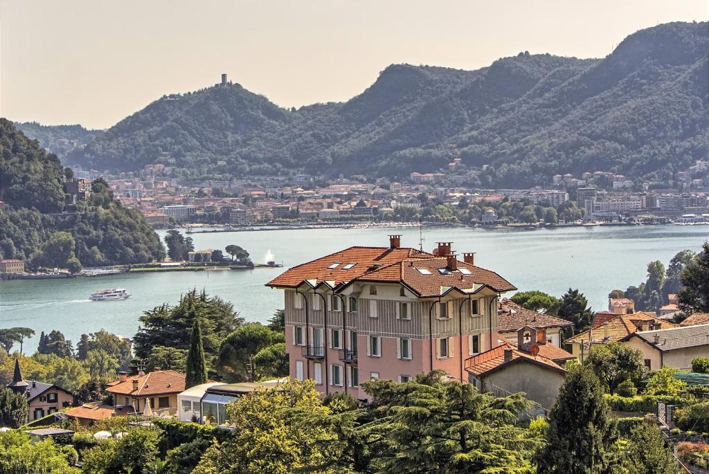 um grande edifício sobre uma colina ao lado de um corpo de água em Hotel Asnigo em Cernobbio