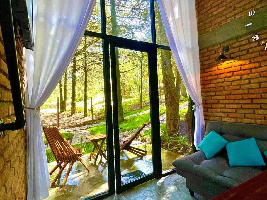 - un salon avec un canapé et une grande fenêtre dans l'établissement Cabaña Hermosa Bosque Fraccionamiento Privado, à Mineral del Chico