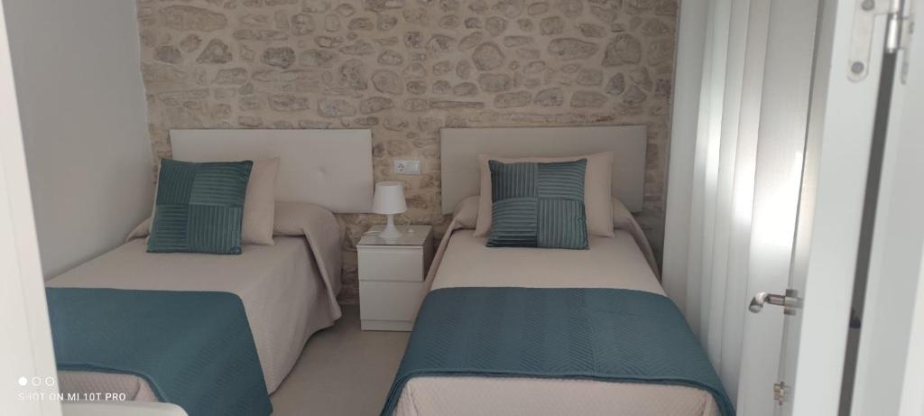two beds in a small room with blue and white at Casa Correos in Medina Sidonia
