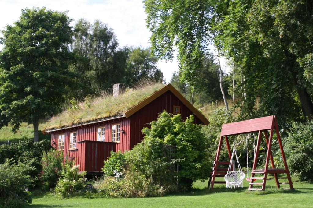 un edificio rojo con techo de hierba y columpio en Åkviktunet hytte Sør, en Averoy