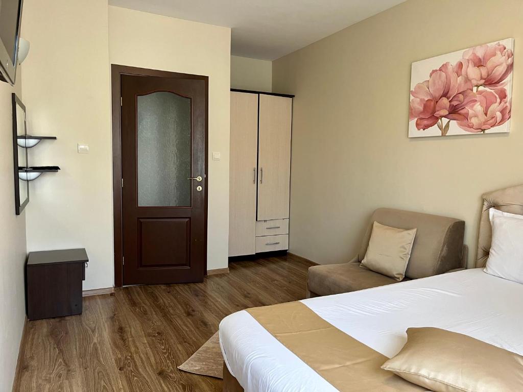 a bedroom with a bed and a chair and a door at Hotel Silver in Sozopol