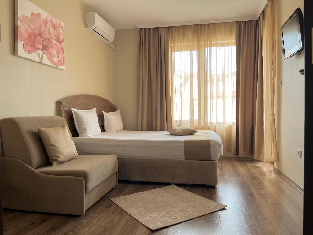 a bedroom with a bed and a chair and a window at Hotel Silver in Sozopol
