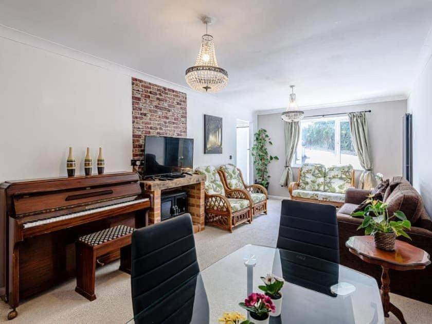 a living room with a piano and a couch at Forest side cottage in Nottingham