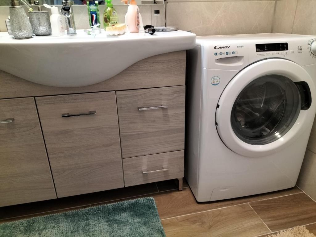 une machine à laver dans une salle de bain à côté d'un lavabo dans l'établissement 250 m dalla spiaggia! Spiaggia libera o attrezzata - LA CASA DI KATE, à Grado