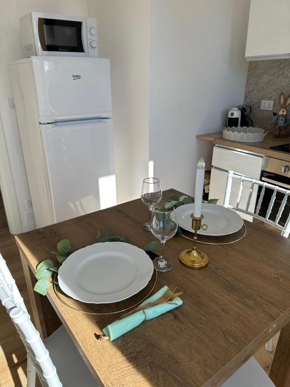 a wooden table with two plates and glasses on it at Casa di Maya in Portacomaro