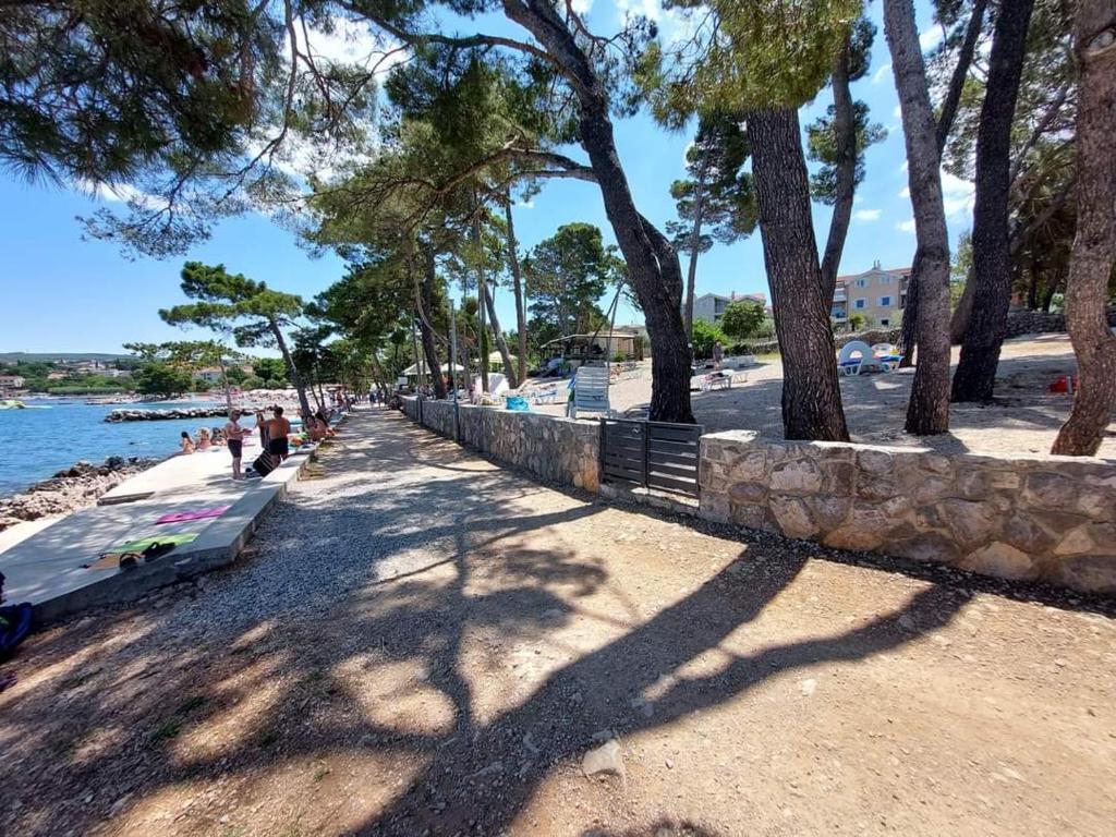 een strand met een bank en bomen en water bij Apartman Amfora in Malinska