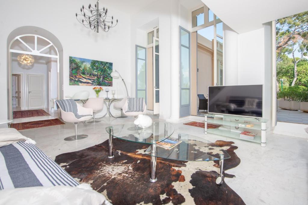 een woonkamer met een tv en een glazen tafel bij Luxurious Historical Suite 2BDR Pool Tennis Private Beach in Roquebrune-Cap-Martin