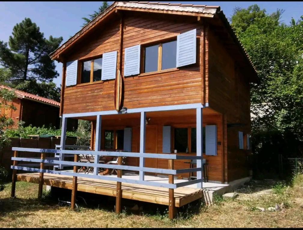 une maison en bois avec une grande terrasse couverte sur un champ dans l'établissement Chalet California Dreamin Route 66, à Casteil