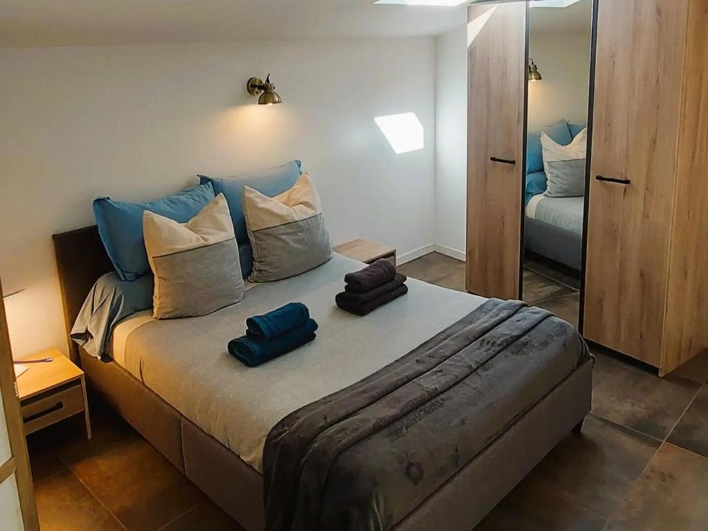 ein Schlafzimmer mit einem Bett mit blauen Kissen und einem Spiegel in der Unterkunft Dépendance Spacieux Duplex 50 M2 Classé 3 étoiles sans vis-à-vis in Gréoux-les-Bains