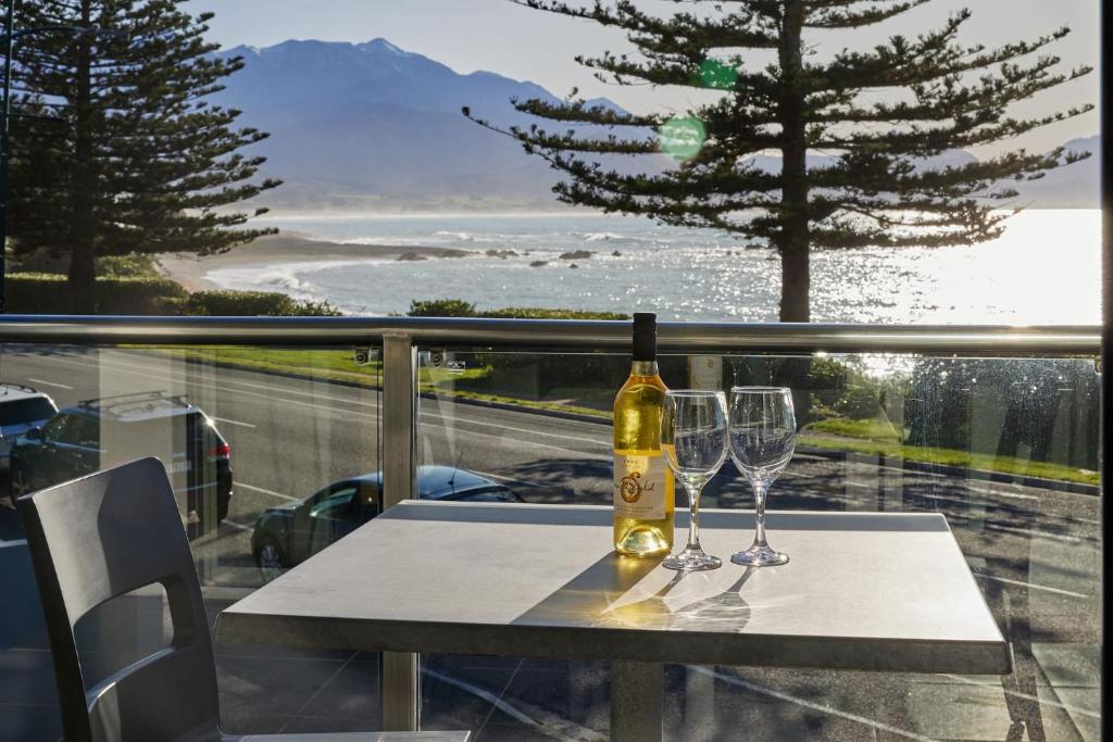 una botella de vino sentada en una mesa con dos copas en Waves on Esplanade - Kaikoura Waterfront Apartment, en Kaikoura