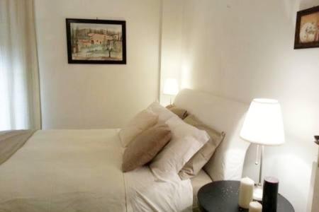 cama blanca con almohadas y lámpara en la habitación en Vomero District Apartment, en Nápoles
