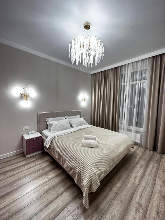 een slaapkamer met een groot bed en een kroonluchter bij ЖК2 Estet 157 in Alma-Ata