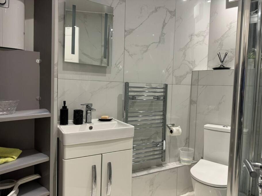 Baño blanco con lavabo y aseo en 1 Bedroom Luxury Flat in Kensington, en Londres