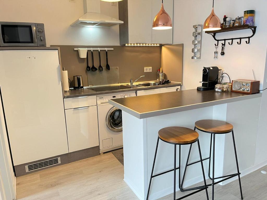 a kitchen with a counter and two stools at Living at Saarpartments with 2 Bedrooms, Netflix - Business & Holiday Apartments for Long- and Short term Stay, 3 min to Train Station and Europa Galerie in Saarbrücken