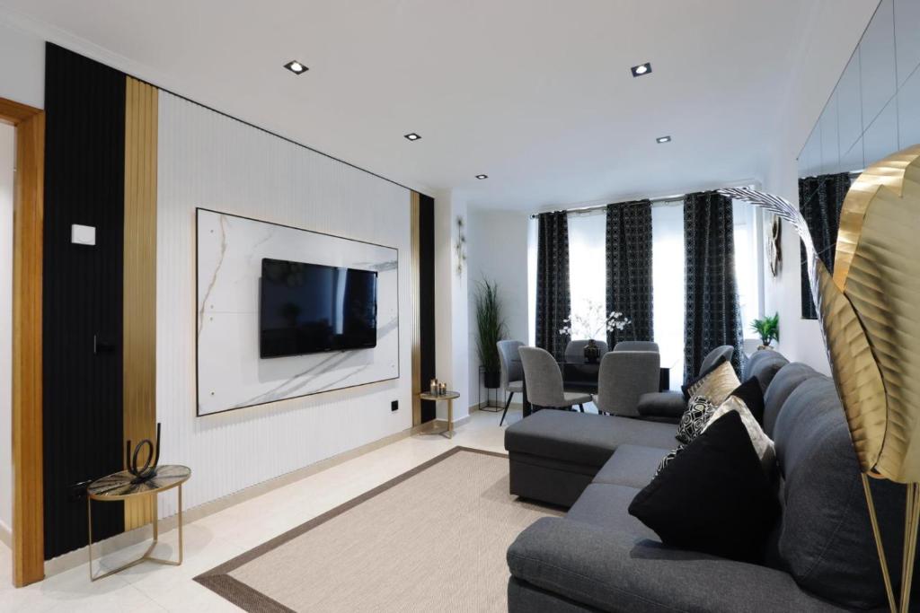sala de estar con sofá y TV en la pared en Apartamento Exclusivo Centrico con parking en Ribadeo