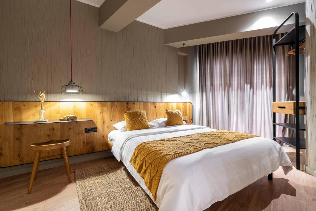 Double bed with wooden headboard, mustard throw and pillows, pendant lights, floor-to-ceiling curtains and open shelving at Maison Bucarest Apartments by Olala Homes in Bucharest