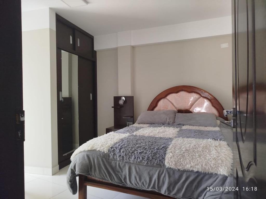 een slaapkamer met een bed met een houten hoofdeinde bij Departamento Trébol in Sucre