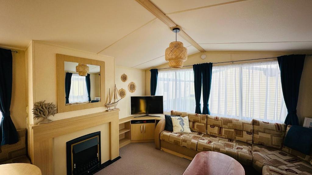 a living room with a couch and a fireplace at Cozy Private Static Caravan at Llyons Robin Hood - Silver Birch Way 11 in Rhyl
