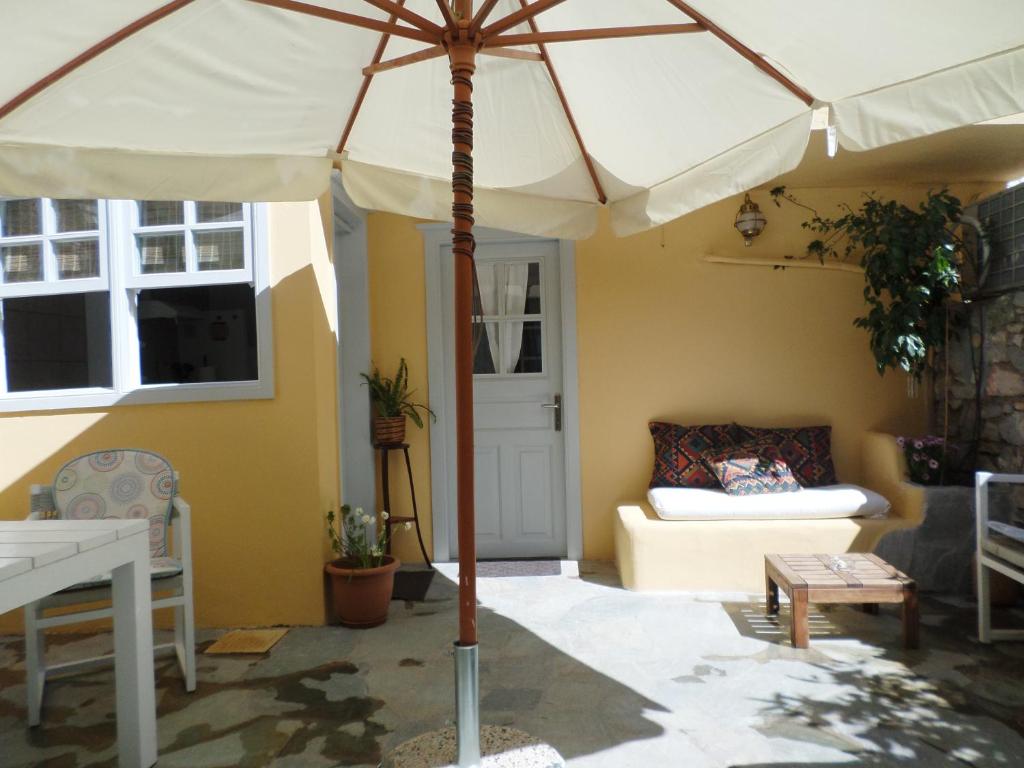 an umbrella in a patio with a couch and a table at In the heart of Hydra in Hydra