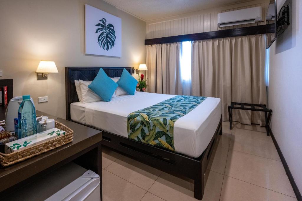 a bedroom with a large bed with blue pillows at Fiji Gateway Hotel in Nadi