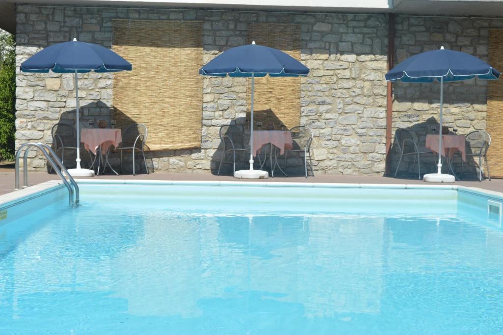 a swimming pool with two chairs and umbrellas at Hotel Belvedere in Passignano sul Trasimeno