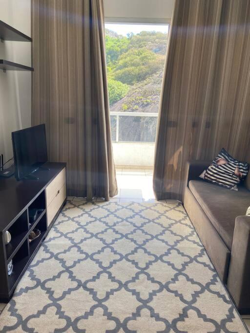 a living room with a couch and a tv and a window at Apartamento bem localizado in Vitória