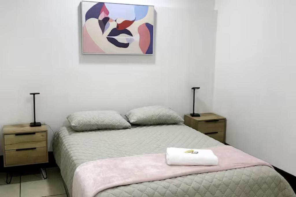 a bedroom with a bed with two night stands and a painting at Casa Colibrí Apartamento 5 in Guatemala