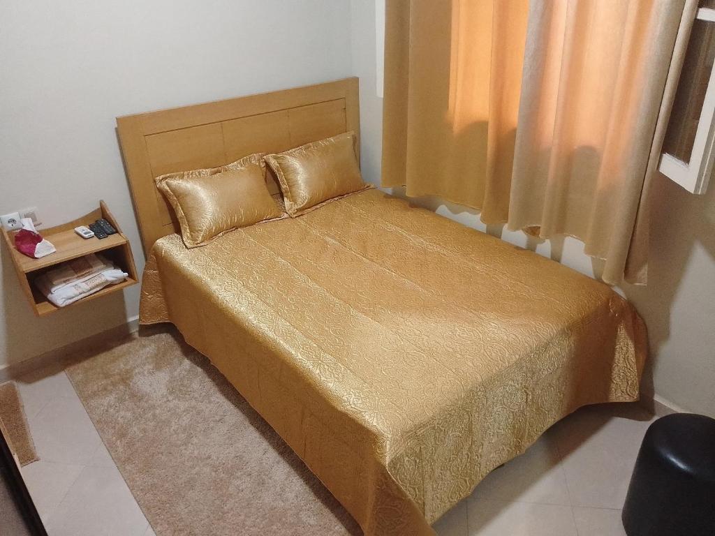 una piccola camera da letto con letto con lenzuola e cuscini dorati di Maison d'hôte Najah a Khenifra