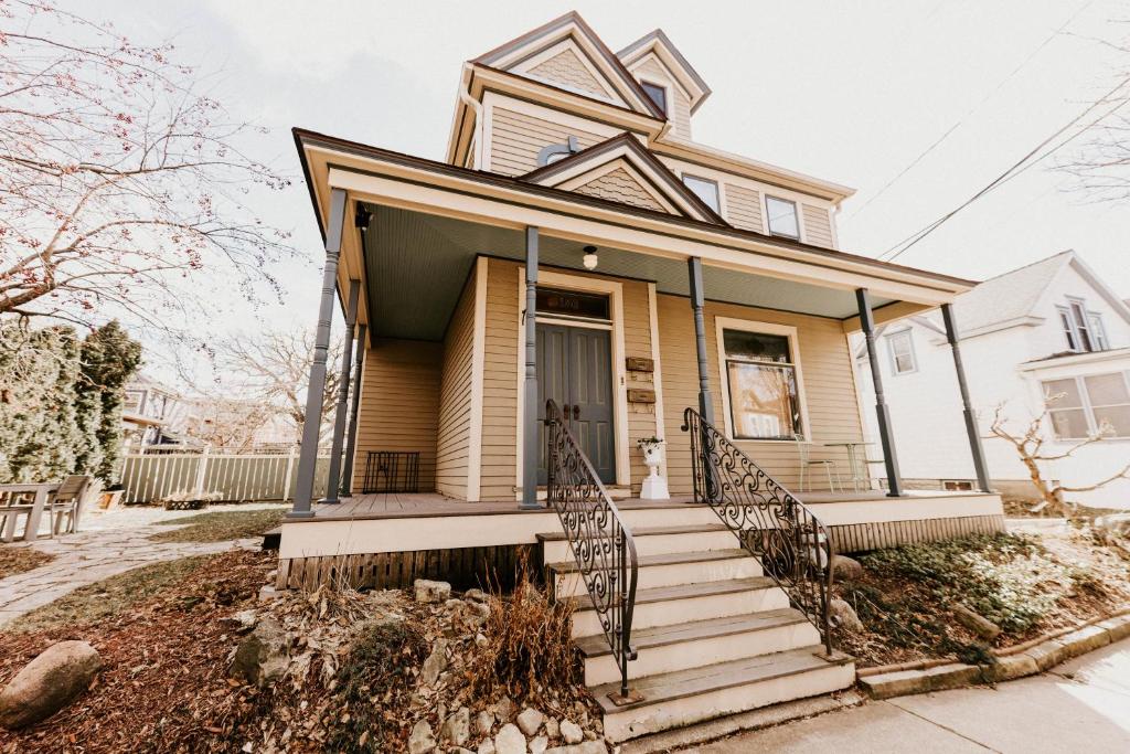 uma casa amarela com um alpendre e escadas em Retro Gem Box Victorian Steps from Irvine Park em Saint Paul