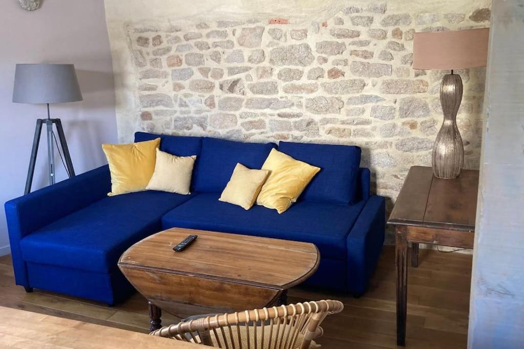 a blue couch with yellow pillows in a living room at Un appart. cosy au cœur d'Etel, à deux pas du port in Étel