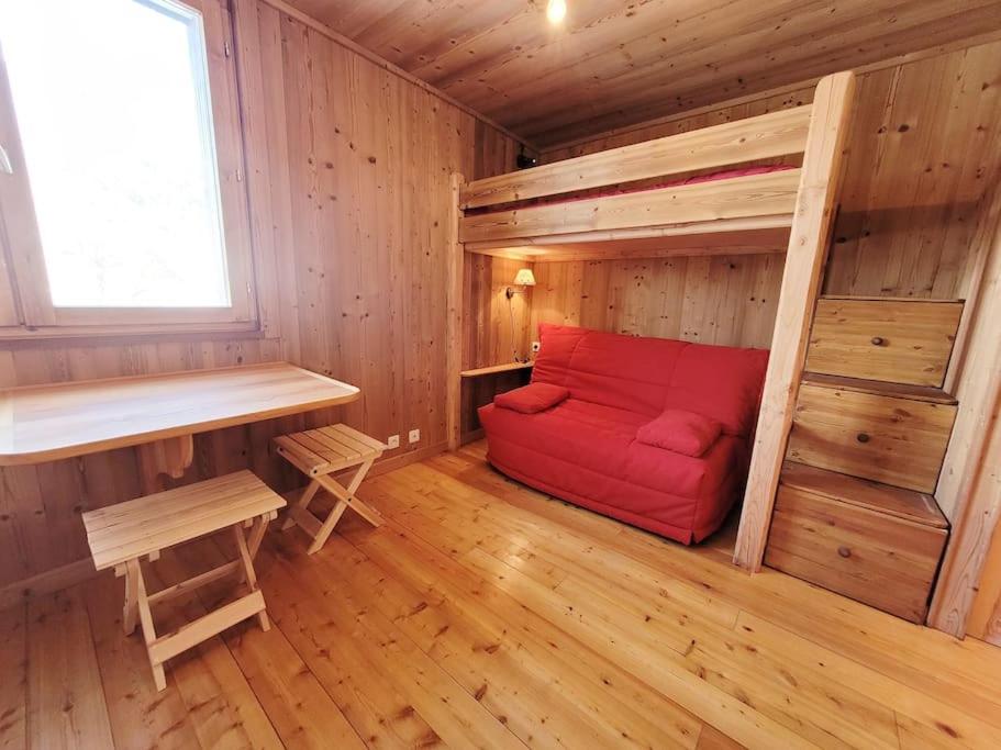 une chambre avec un canapé rouge dans une cabane en bois dans l'établissement Studio pour 3 personnes au pied des pistes, à La Salle Les Alpes