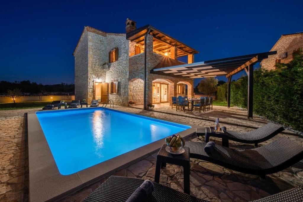 - une piscine en face d'une maison la nuit dans l'établissement Villa Mani, à Butkovići