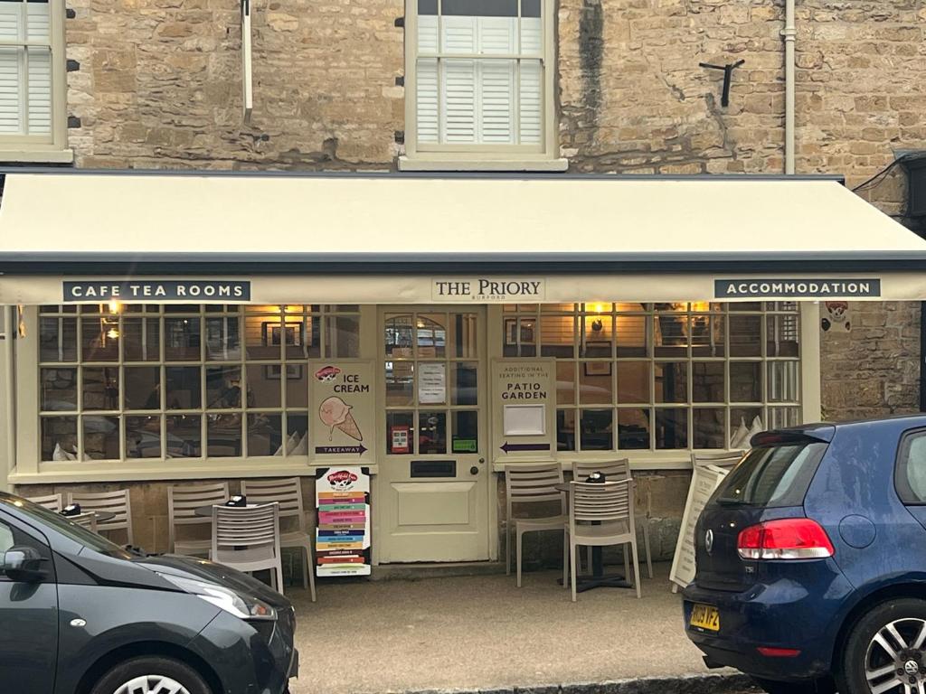 ein Restaurant mit Stühlen vor einem Gebäude in der Unterkunft Priory Tearooms Burford with Rooms in Burford