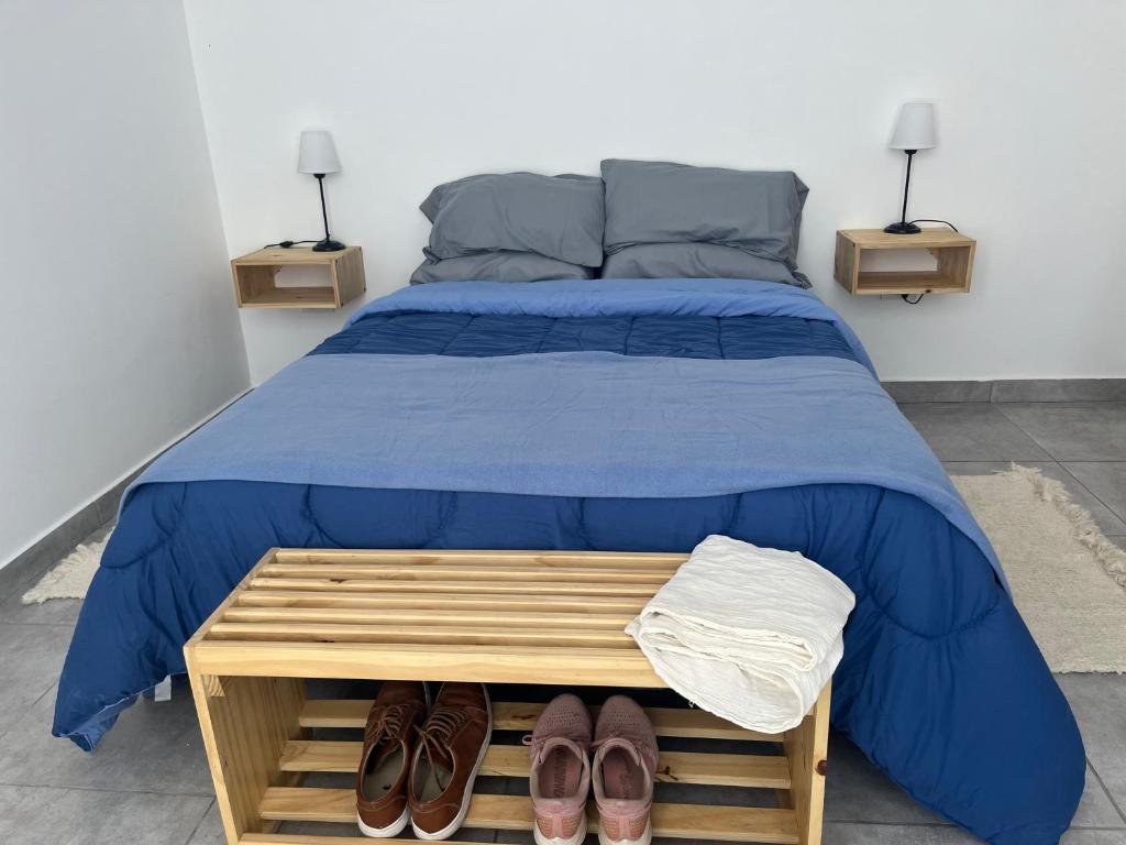 - une chambre dotée d'un lit avec des draps bleus et des chaussures dans l'établissement Te veo bien, à Suipacha