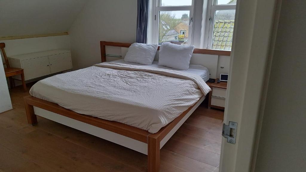 a bedroom with a bed with white sheets and a window at L'appel Studio near Amsterdam in Warder