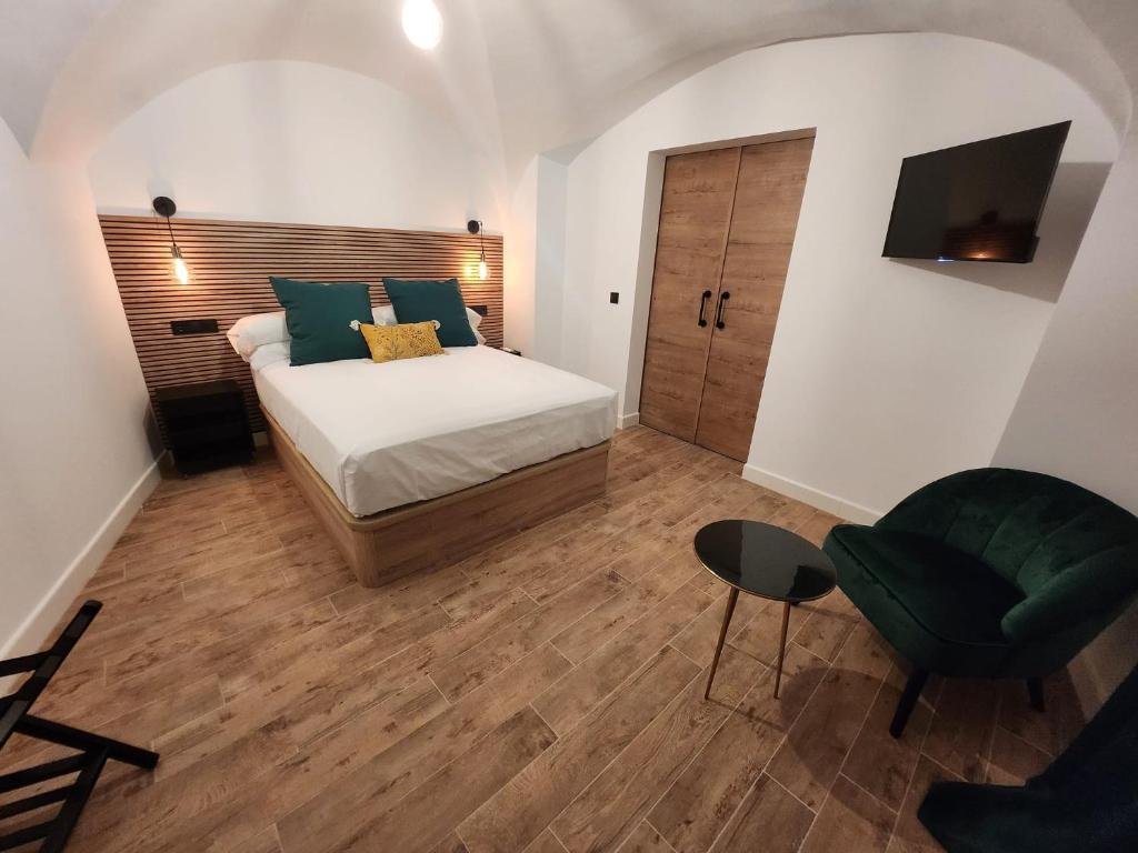 - une chambre avec un lit et une chaise verte dans l'établissement Bailén 3, à Cáceres