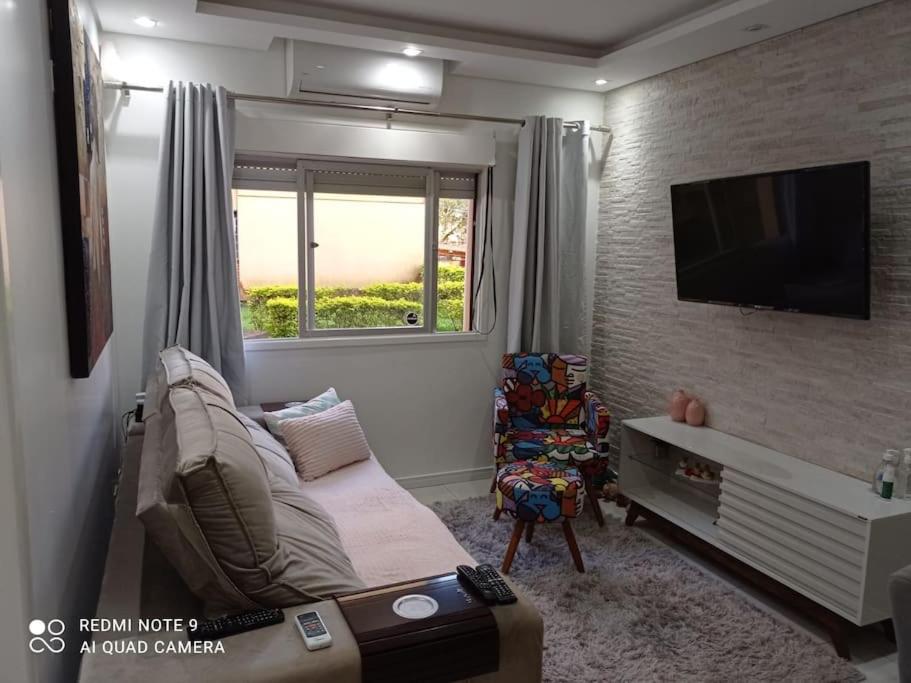 een woonkamer met een bank en een flatscreen-tv bij Apartamento Aconchegante para duas pessoas in Gravataí