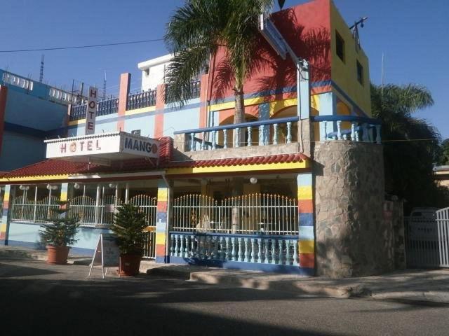 a colorful building with a palm tree in front of it at Hotel Mango in Boca Chica