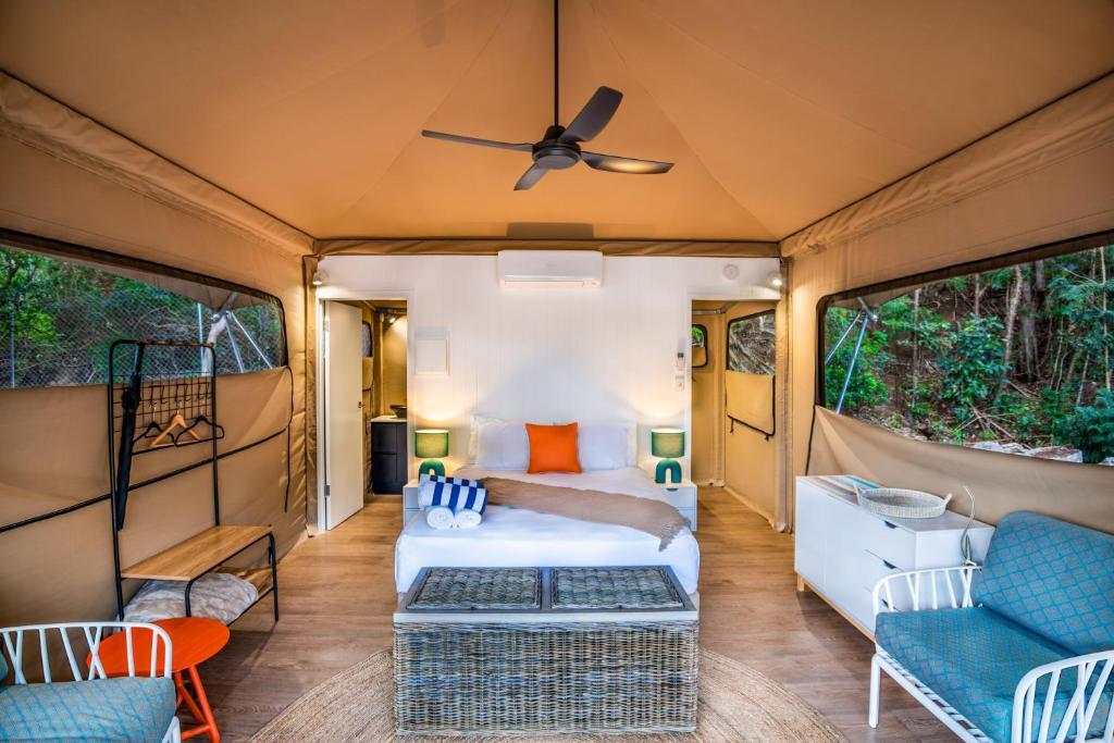 1 dormitorio en una cabaña con 1 cama y sillas en DeluxeQueenSafariTent1, en Nelly Bay