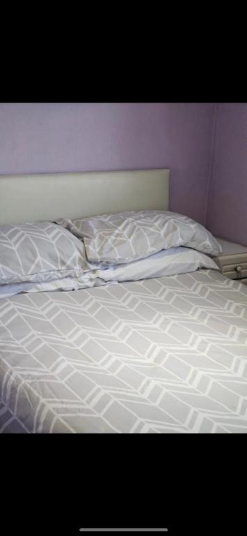 uma cama não feita com lençóis e almofadas brancas em 2 Bedroom Chalet Isle of Sheppey Holiday Village em Kent