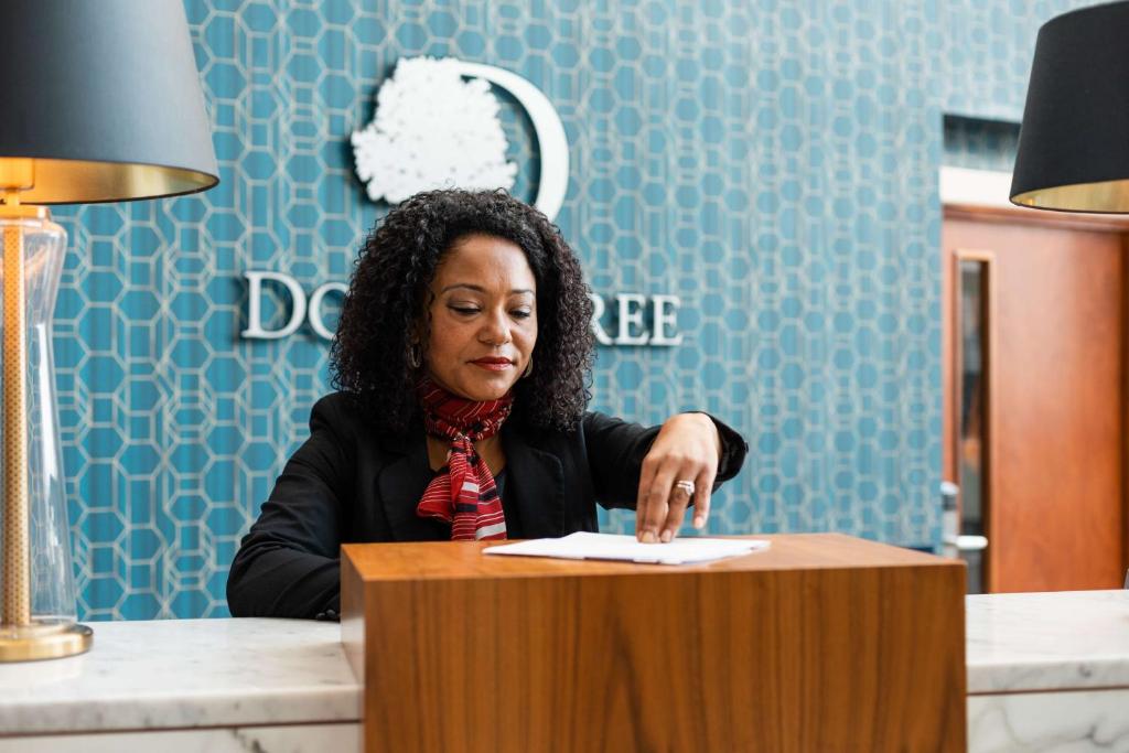 a woman sitting at a table with a paper at DoubleTree by Hilton Hotel Newcastle International Airport in Newcastle upon Tyne