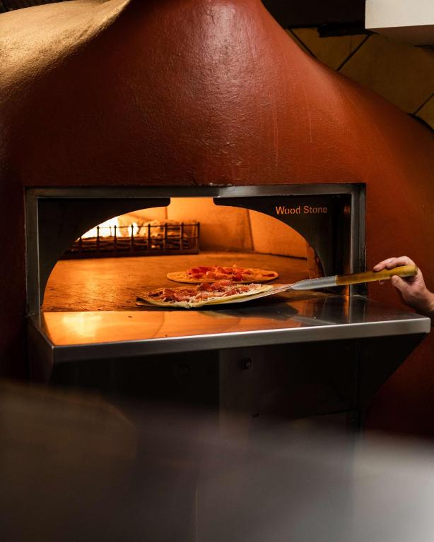 a person taking a pizza out of an oven at DoubleTree by Hilton Hotel Newcastle International Airport in Newcastle upon Tyne