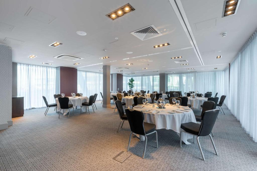 a dining room with tables and chairs and windows at DoubleTree by Hilton Hotel Newcastle International Airport in Newcastle upon Tyne