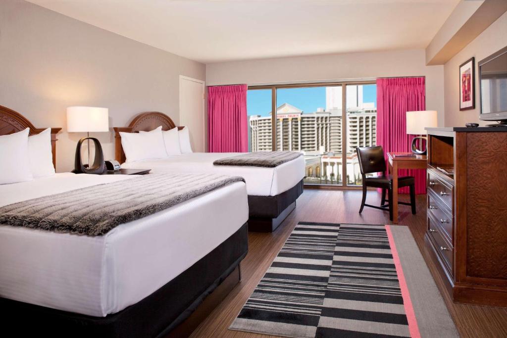 a hotel room with two beds and a balcony at Attractive Modern Unit by Flamingo Strip Las Vegas in Las Vegas