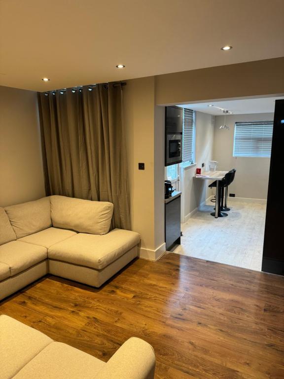 a living room with a couch and a kitchen with a piano at A double bedroom in Nice house in London