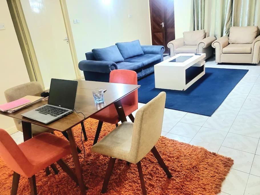 a living room with a table with a laptop on it at SwanLakeview3br, Wi-Fi, Netflix, Balcony, Sunset. in Kisumu